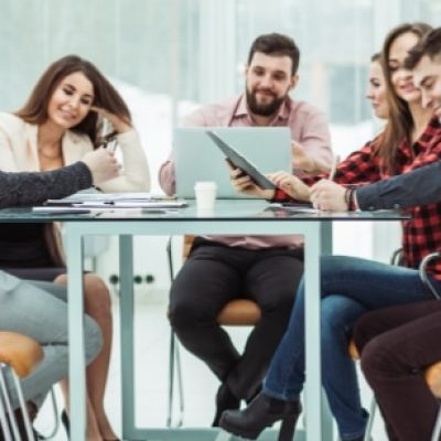 Eine Gruppe Mitarbeiter sitzen an einem Tisch und arbeiten mit dem Laptop